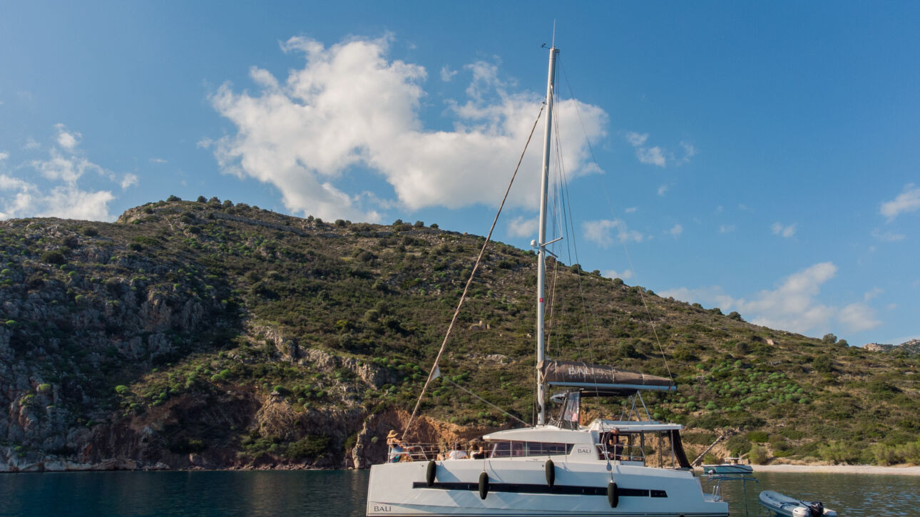 Sailawave catamaran anchored in a calm bay below green hills